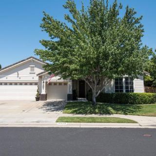 A suburban house with a two-car garage and a tree in the front yard.