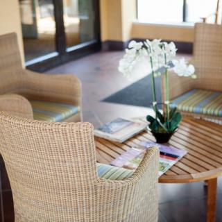 A cozy waiting area with wicker chairs, a wooden table, and a potted orchid as a centerpiece.