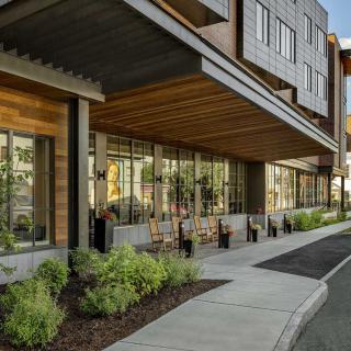 A modern commercial building with large glass windows and landscaped surroundings.