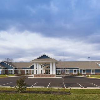 A modern building with a spacious parking lot under a cloudy sky.