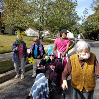 A group of elderly people enjoying a walk outdoors in the neighborhood on a sunny autumn day.