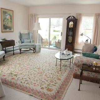 A traditional living room with elegant furniture, including a grandfather clock and a large floral rug.