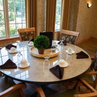 An elegantly set round dining table with napkins and glasses in a well-lit room.