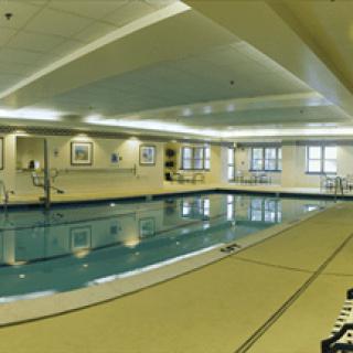 An indoor swimming pool with bright lighting and tiled surroundings.