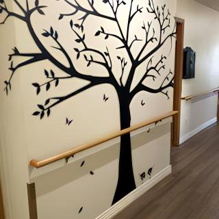 A hallway featuring a tree mural with a handrail along the wall.