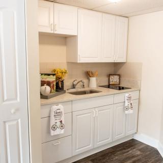 A cozy kitchen setup featuring white cabinets, a sink, and decorative items on the countertop.
