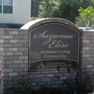 Sign for Suzanne Elise Assisted Living Community mounted on a brick wall.