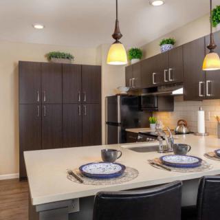 A modern kitchen with sleek cabinetry, pendant lighting, and a stylish countertop dining area.