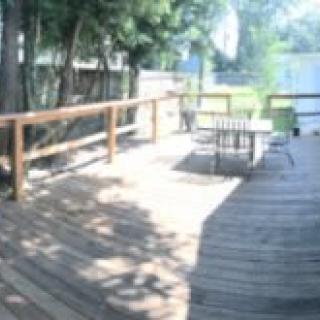A sunny outdoor deck with patio furniture and surrounding trees.
