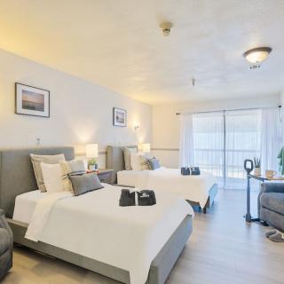 A modern hotel room with two neatly made beds, light decor, and comfortable furnishings.