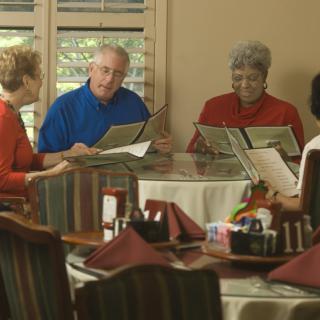 A group of seniors looking at menus while dining together in a restaurant.