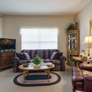 A cozy living room with a striped sofa, coffee table, and a television set.