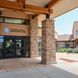 The entrance of a modern school building with stone pillars and large windows.