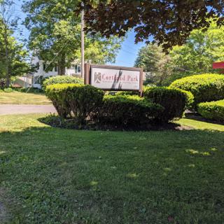 A beautifully landscaped area featuring a sign surrounded by lush greenery and a clear blue sky.