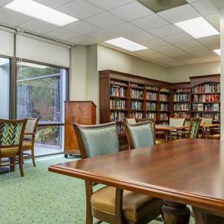 A quiet library reading area with bookshelves, tables, and chairs.