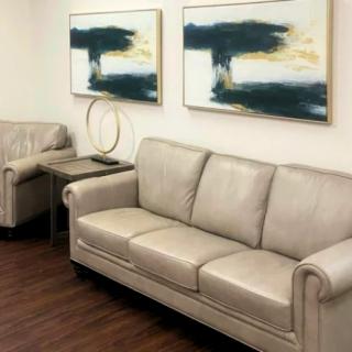 A modern living room featuring a beige leather sofa and abstract artwork on the walls.