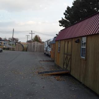 A quiet scene featuring a row of wooden sheds with a red roof in an outdoor setting.