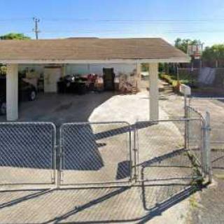 A fenced driveway leading to a garage in a residential area.