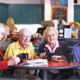 A group of seniors enjoying coffee together in a cafe.