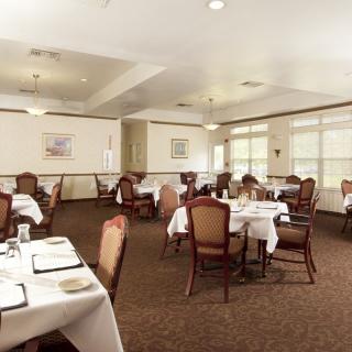 An elegantly furnished dining room with neatly arranged tables and chairs, ready for guests.