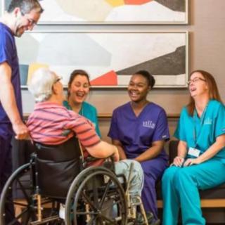 A team of healthcare professionals engaging with a patient in a wheelchair, creating a warm and friendly atmosphere.