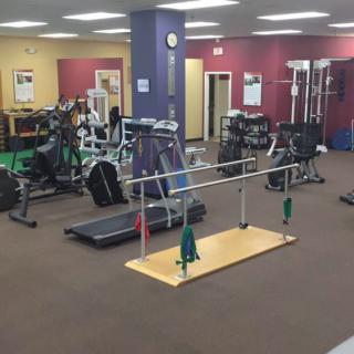 A spacious gym with various exercise equipment including treadmills, weights, and parallel bars.