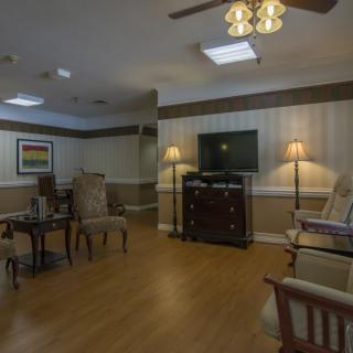 A cozy living room with comfortable chairs, a TV, and soft lighting.
