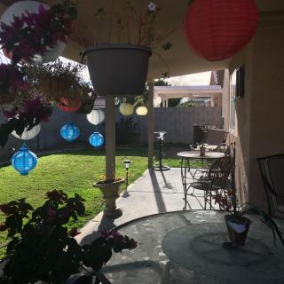 A sunny patio adorned with colorful lanterns, outdoor furniture, and lush plants.