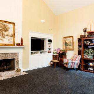 A cozy living room featuring a fireplace, an armchair, and a bookshelf.