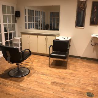 An empty hair salon with wooden flooring and mirrors on the wall.
