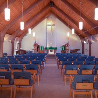 A view of a church interior with rows of pews leading up to the altar.