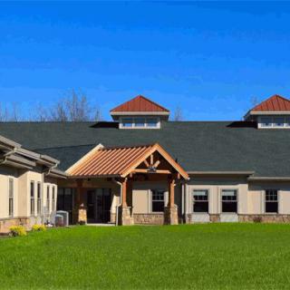 A modern building with a gabled roof and large grassy lawn under a clear blue sky.