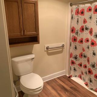A cozy bathroom featuring a toilet, floral shower curtain, and wooden cabinetry.