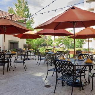 A sunny outdoor patio with tables and umbrellas, ready for dining.