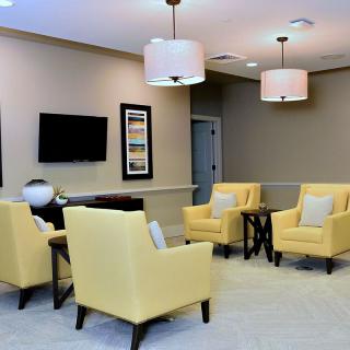 A modern living room featuring yellow chairs, a television, and elegant lighting.