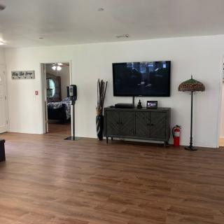 A spacious living room featuring a television mounted on the wall with minimalist decor and wooden flooring.