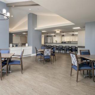 A modern and spacious dining area with tables, chairs, and a kitchen in the background.