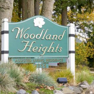 A welcome sign for Woodland Heights surrounded by trees and greenery.