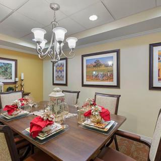 A beautifully decorated dining room with a wooden table set for dinner, featuring elegant wall art and an ornate chandelier.