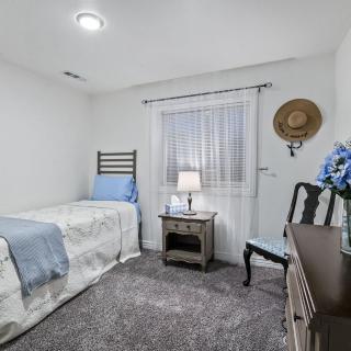 A cozy bedroom featuring a single bed, nightstand with lamp, and simple decor.