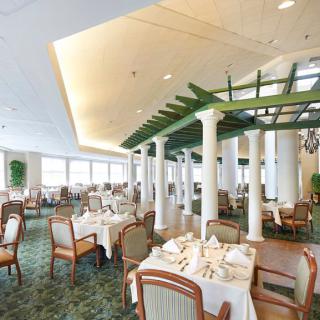 An elegant dining area with neatly arranged tables and chairs, featuring decorative elements in the ceiling.