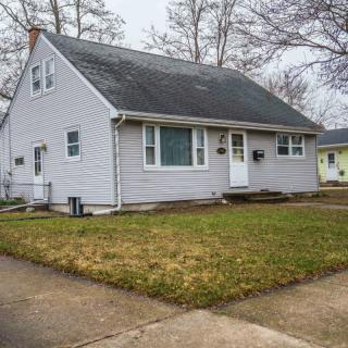 A suburban house with a neatly trimmed lawn and a sloped roof.