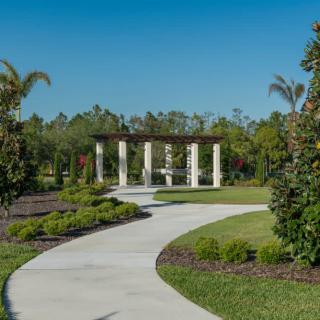 A scenic garden pathway lined with trees and leading to a structure with columns.