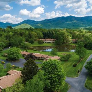 A scenic aerial view of buildings surrounded by lush greenery, with mountains in the background.