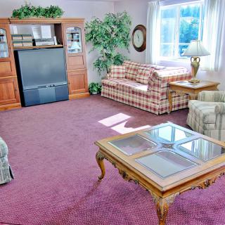 A cozy living room with a large television, plaid sofa, and wooden coffee table.