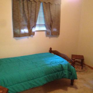 A simple bedroom with a single bed and a small window.