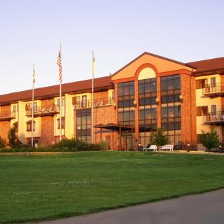 A hotel building with a well-maintained lawn and multiple flags displayed in front.
