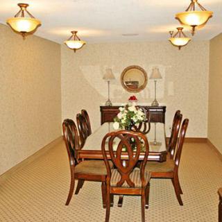 A well-lit dining room with a table and chairs, featuring elegant lighting and a decorative mirror on the wall.