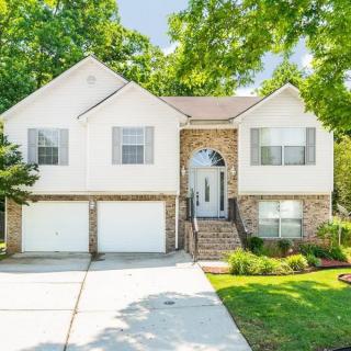 A beautiful two-story house with a well-maintained driveway and lush greenery.