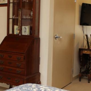 A cozy bedroom interior featuring a wooden cabinet and a mounted television.